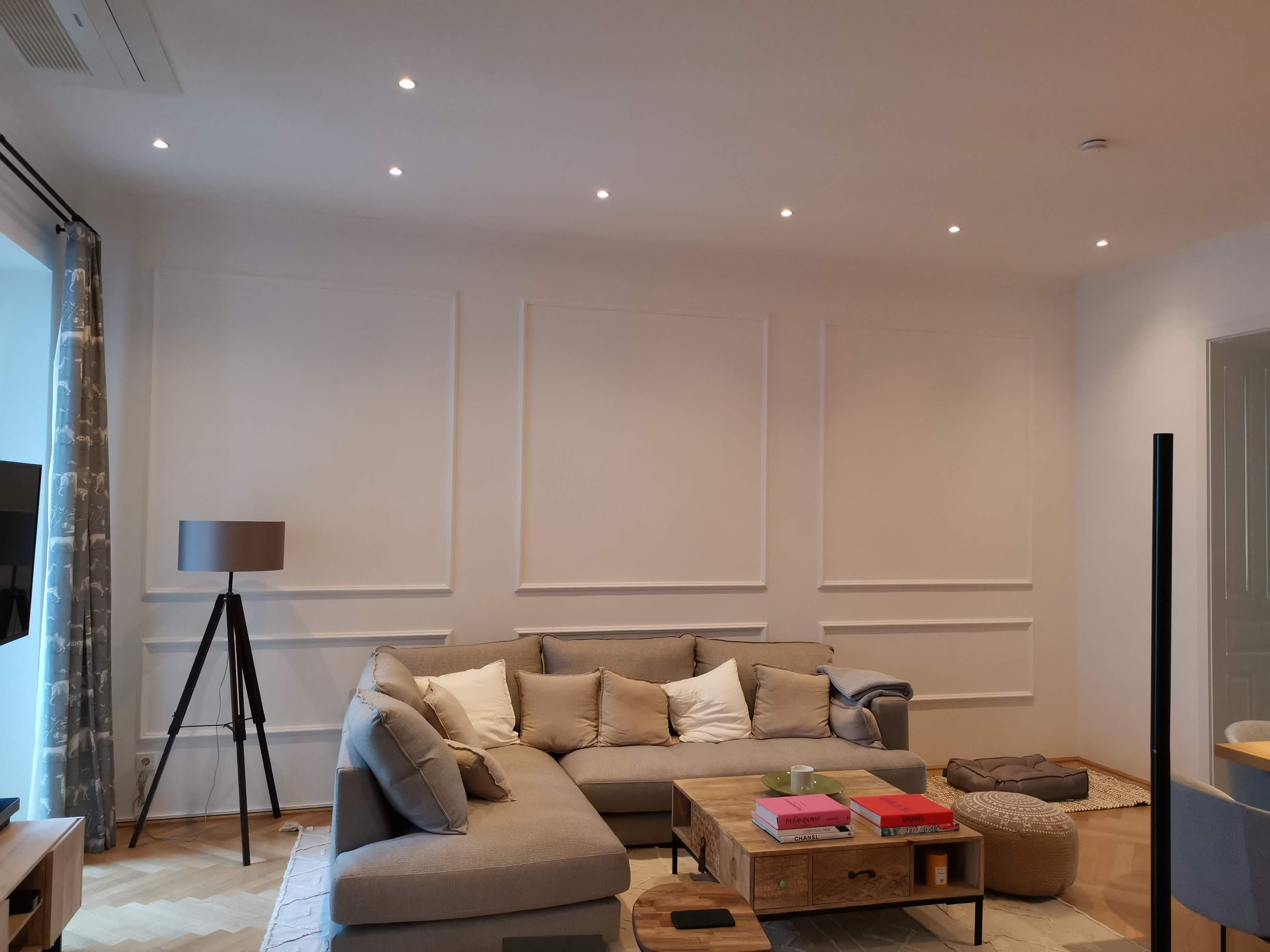 Innenansicht eines weiß gestrichenen Raumes mit großem Sofa, Stehlampe und Couchtisch